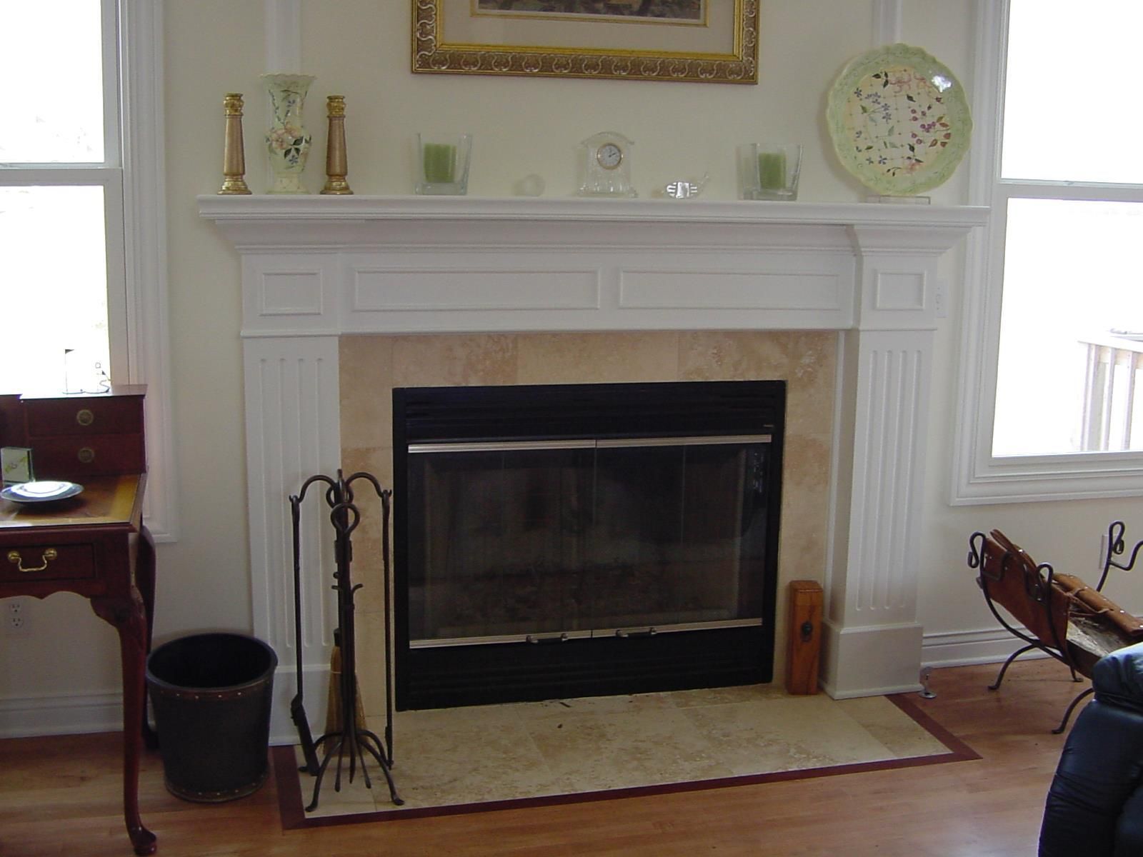 Fireplace with cream mantel and beige stone surround, decorated with art and decor.