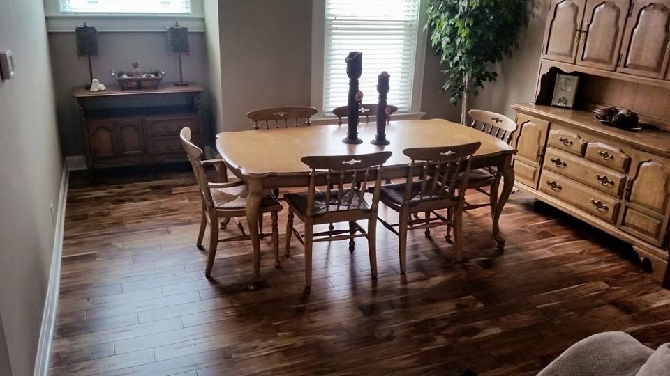 Dining room with a wooden table, chairs, buffet, and hutch; hardwood floors and window.
