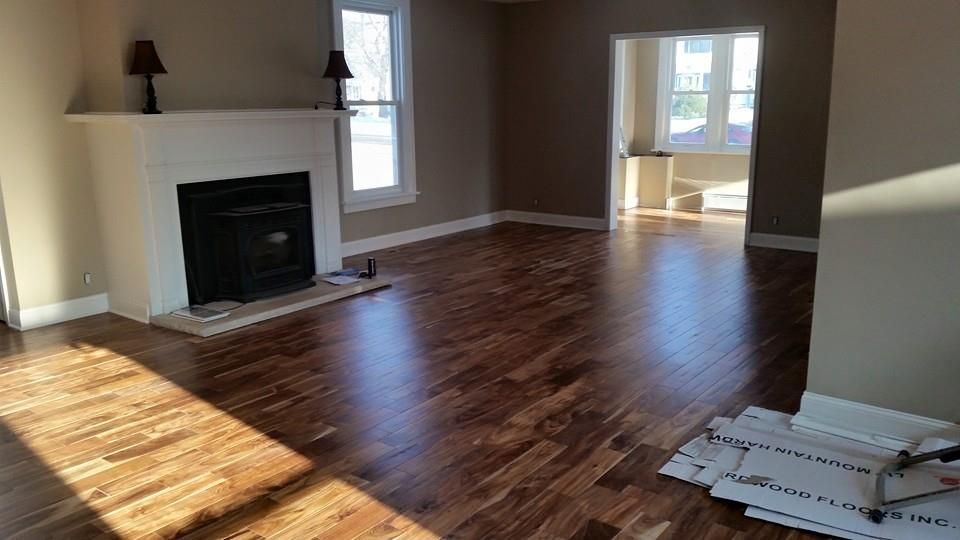 Living room with hardwood floors, fireplace, and window, bathed in sunlight.