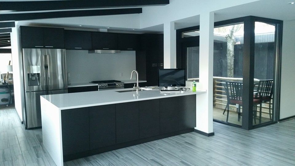 Modern kitchen with dark cabinetry, stainless steel appliances, and a gray countertop island.