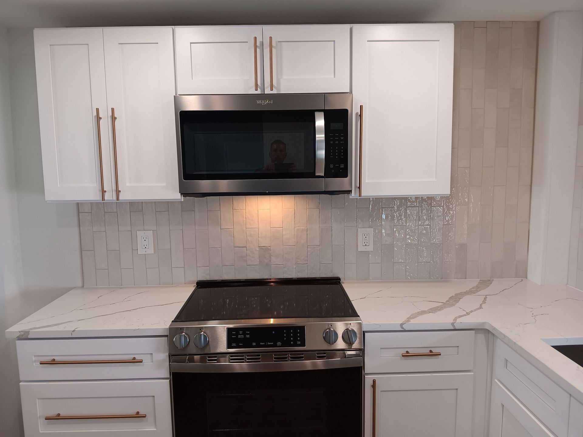 White kitchen cabinets with stainless steel appliances and white countertops.