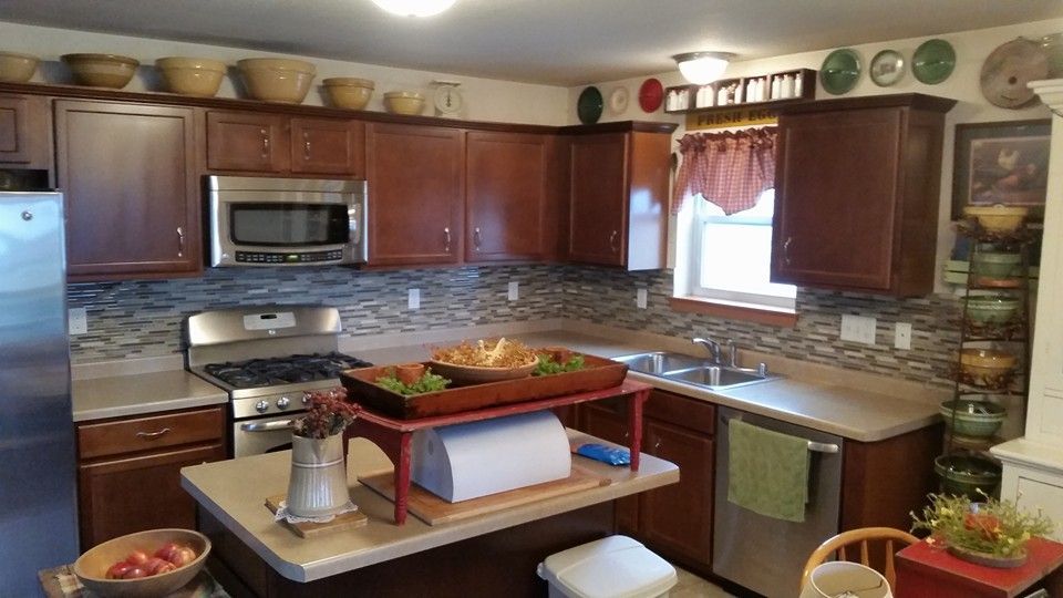 Kitchen with dark brown cabinets, stainless steel appliances, and island with a wooden tray of food.