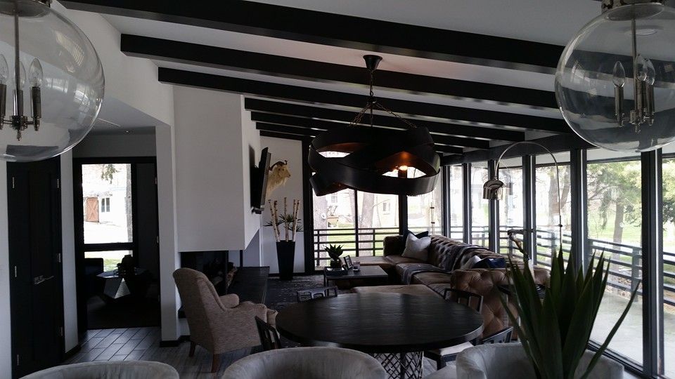 Living room with black beams, globe lights, and large windows overlooking a balcony.