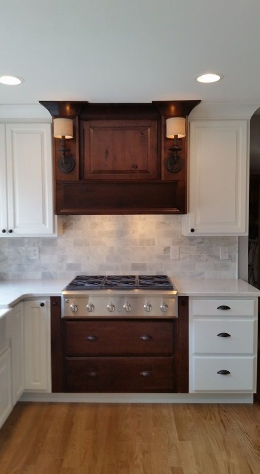Kitchen with a dark wood range hood and cabinetry, a stainless steel stove, and white cabinets.