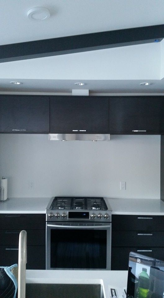 Kitchen with dark cabinets, stainless steel stove, and white backsplash.
