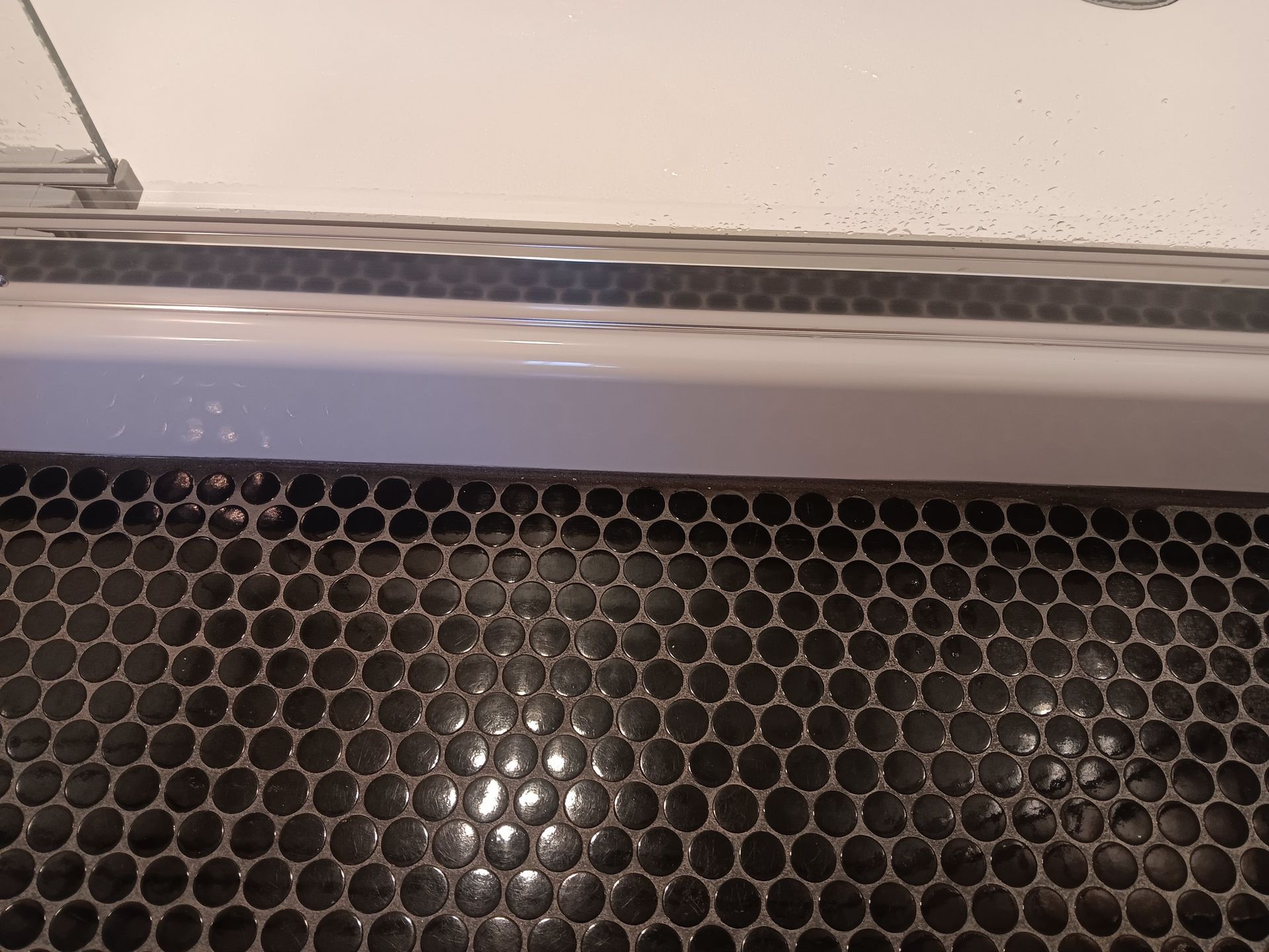 Black penny tile floor with a white bathtub edge.