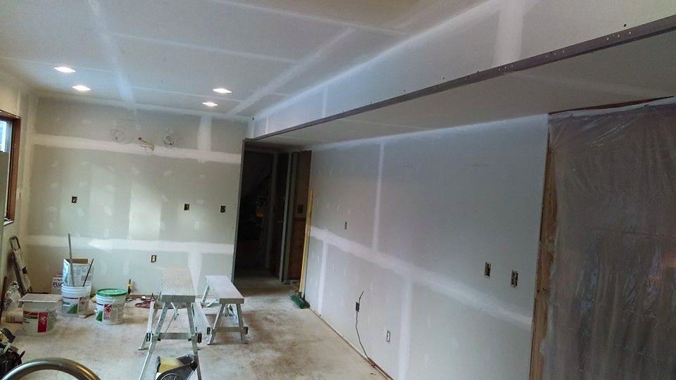 Interior room under construction, with drywall installation and recessed lighting.