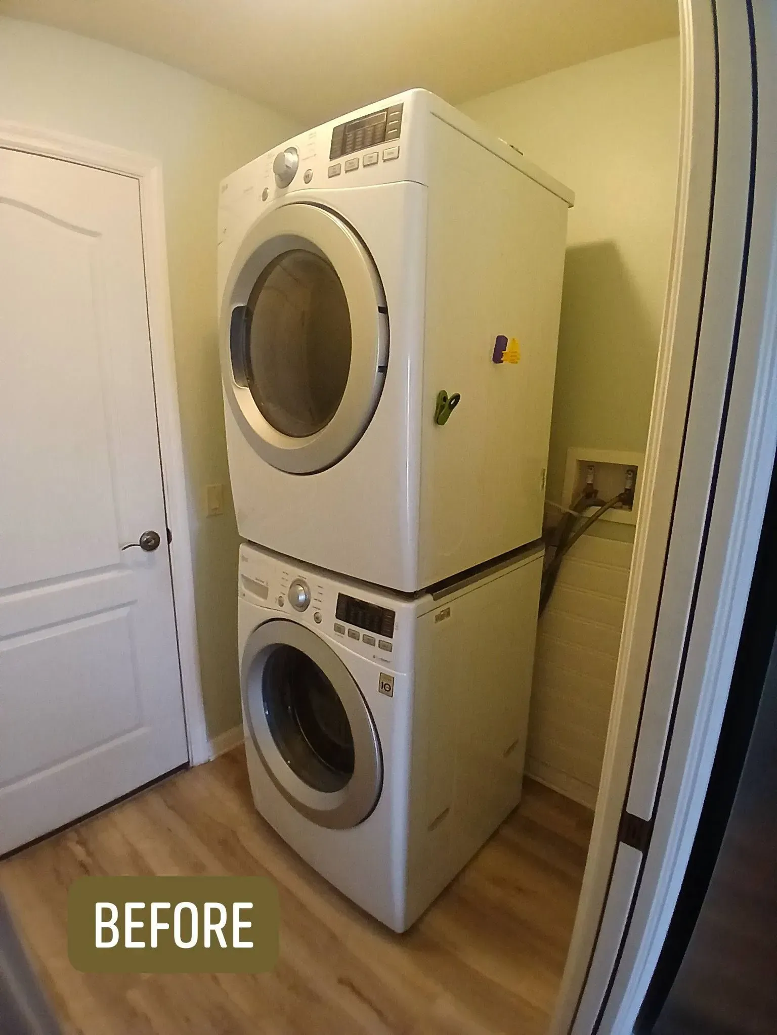 Stacked white washer and dryer in a laundry room, next to a door.