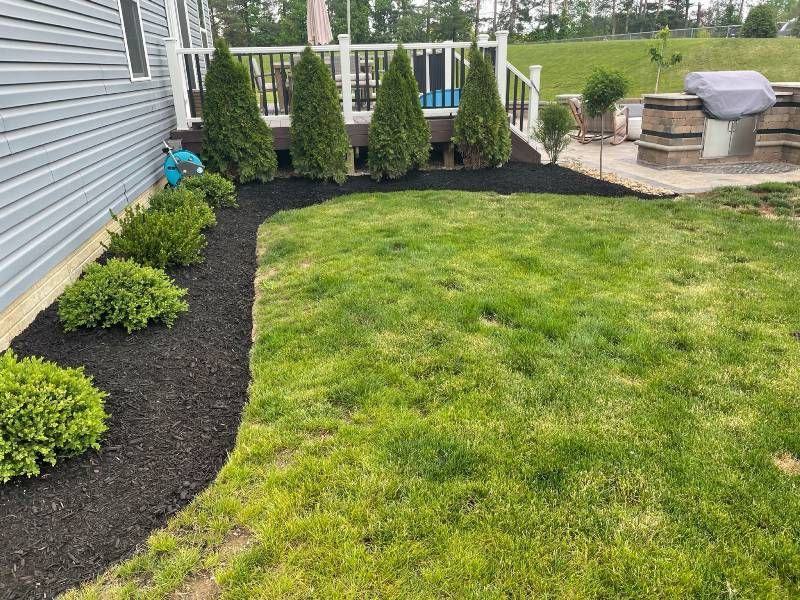 A lush green lawn in front of a house with a deck.