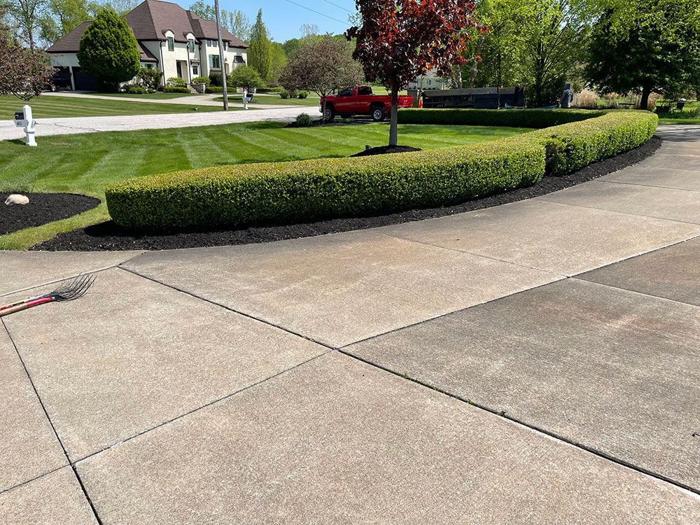 A concrete driveway leading to a house with a red truck parked in the driveway.