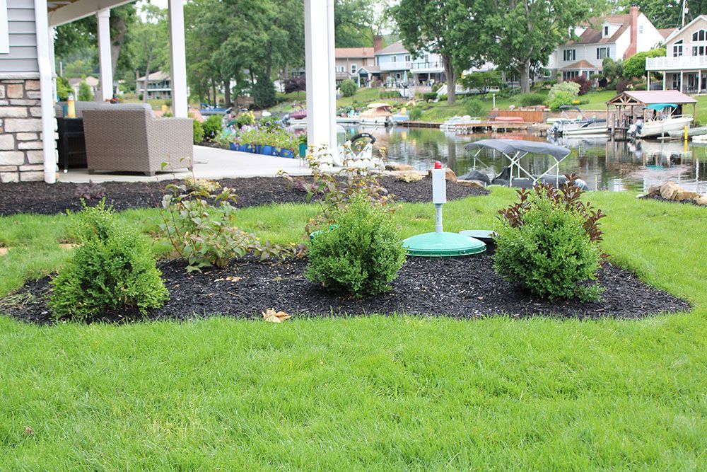 A lush green lawn in front of a house next to a body of water.