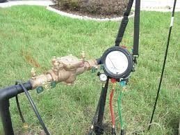 A hose with a gauge attached to it is sitting in the grass