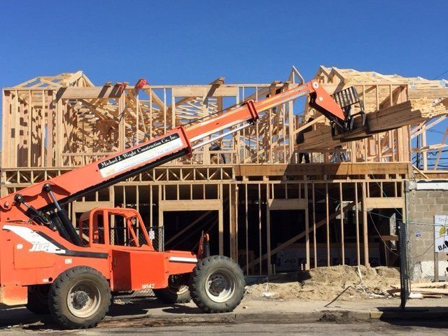An orange forklift lifting wood planks