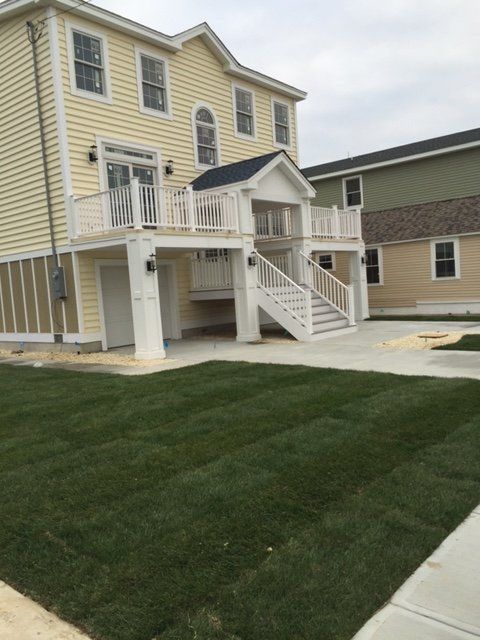 A large yellow house with a white deck and stairs