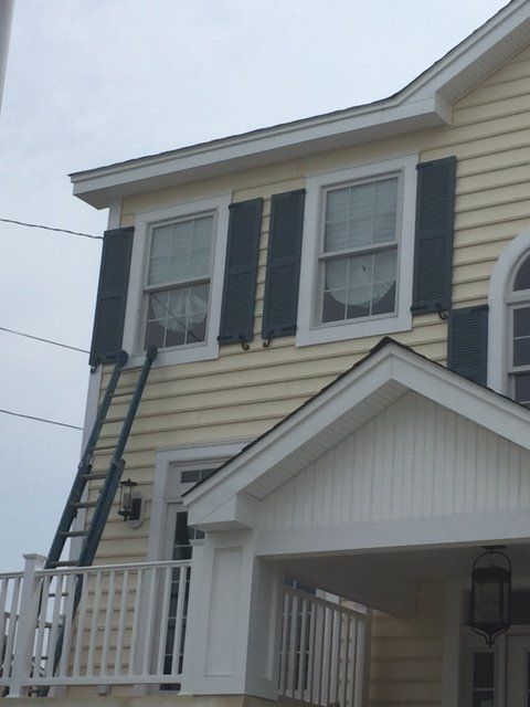 A yellow house with black shutters on the windows