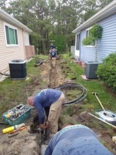 A man is digging in the dirt in front of a house