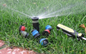 A sprinkler is spraying water on a lush green lawn