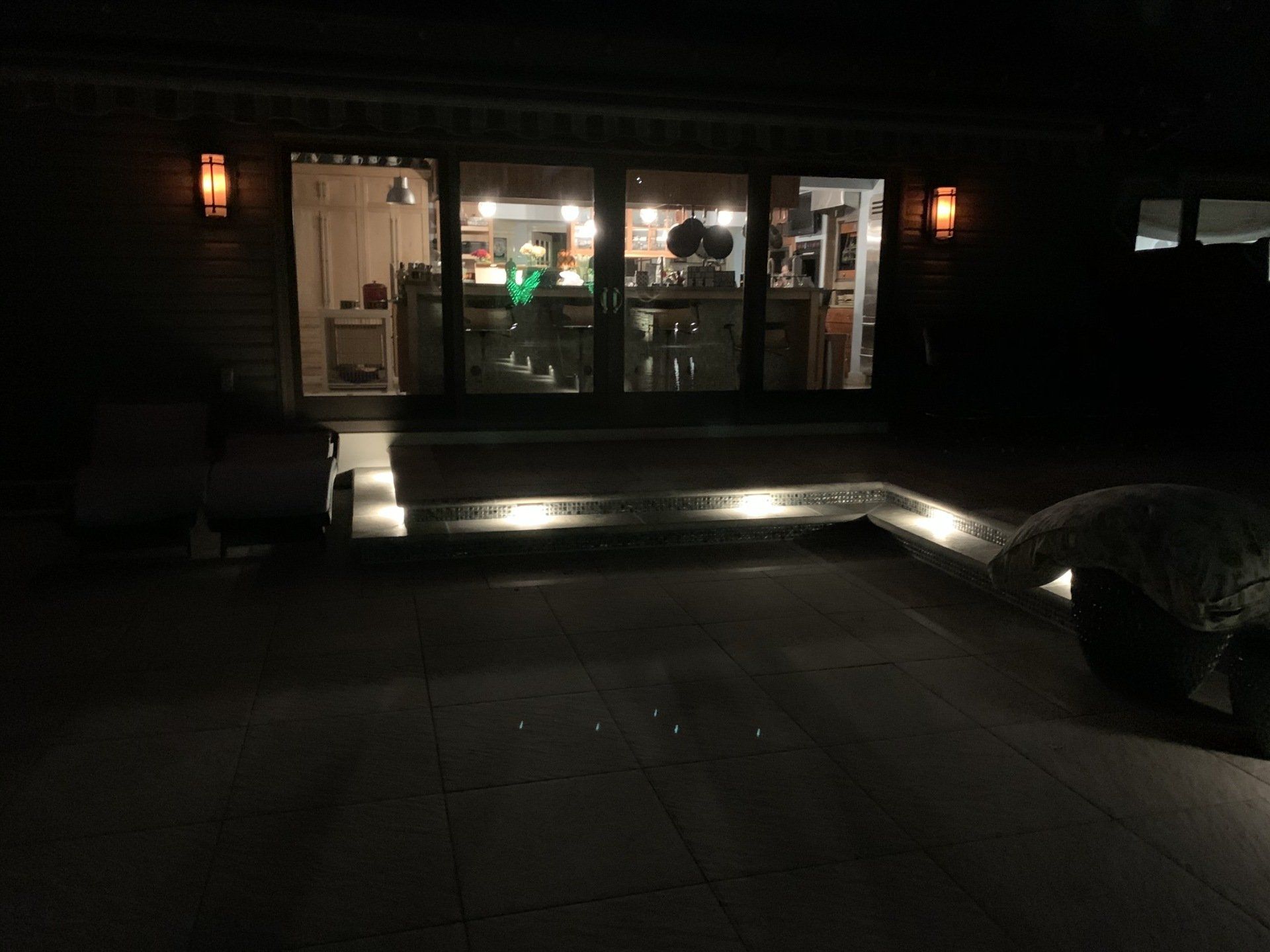 A house with sliding glass doors is lit up at night