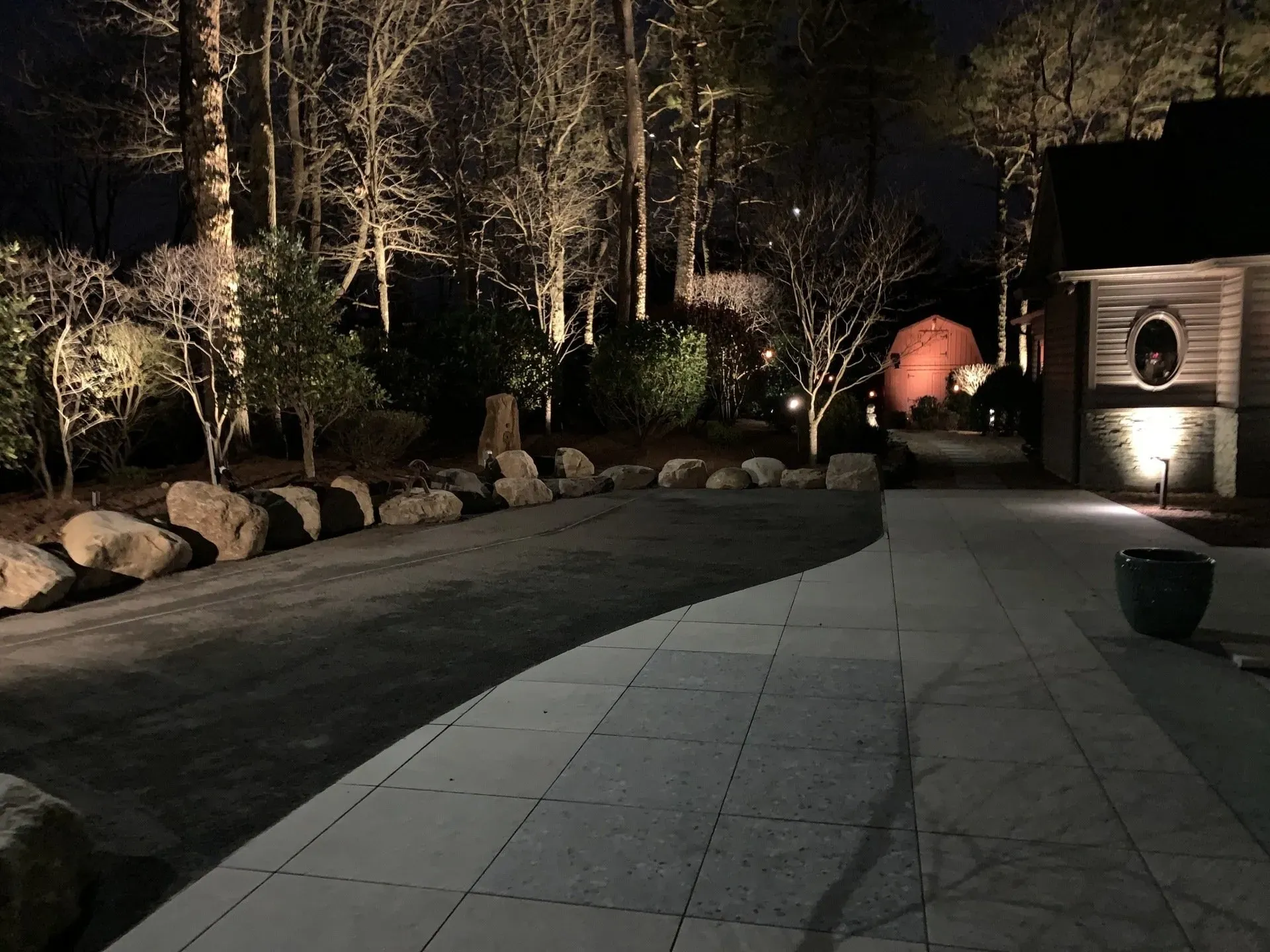 A patio is lit up at night with trees in the background