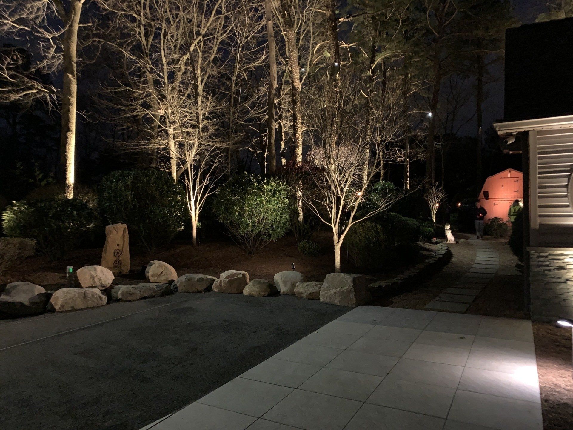 A patio is lit up at night with trees in the background