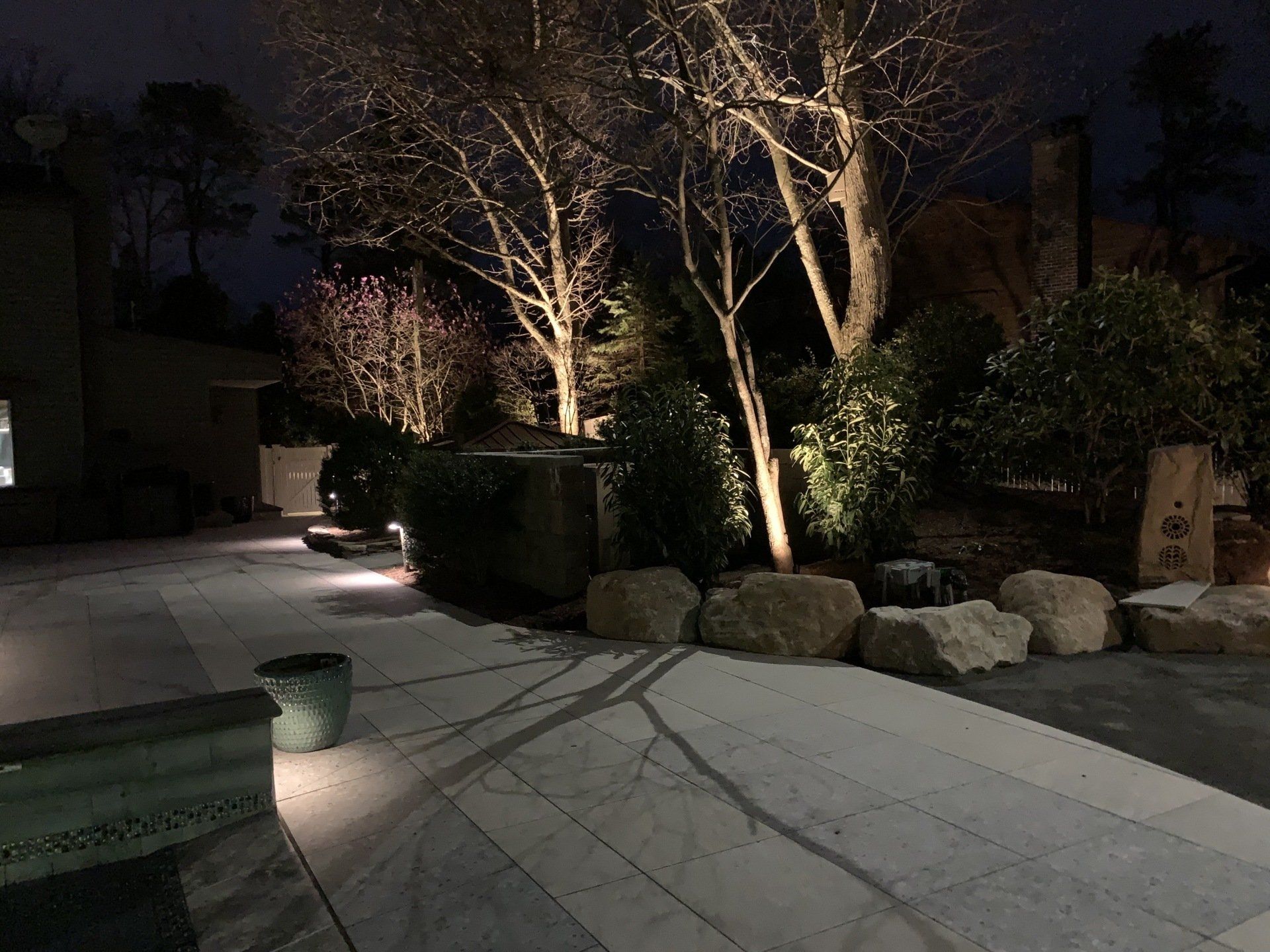 A patio is lit up at night with trees in the background