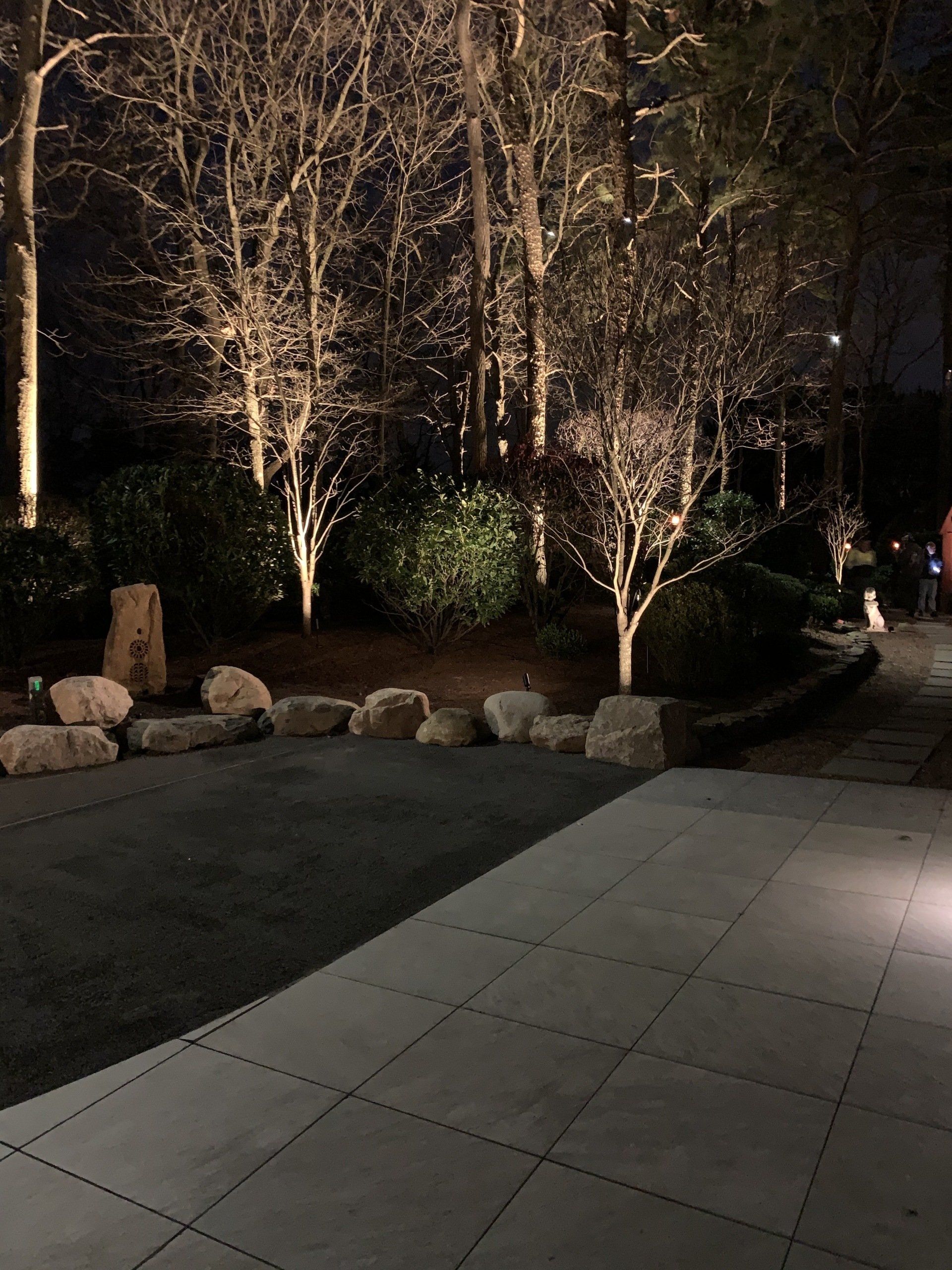 A patio is lit up at night with trees in the background