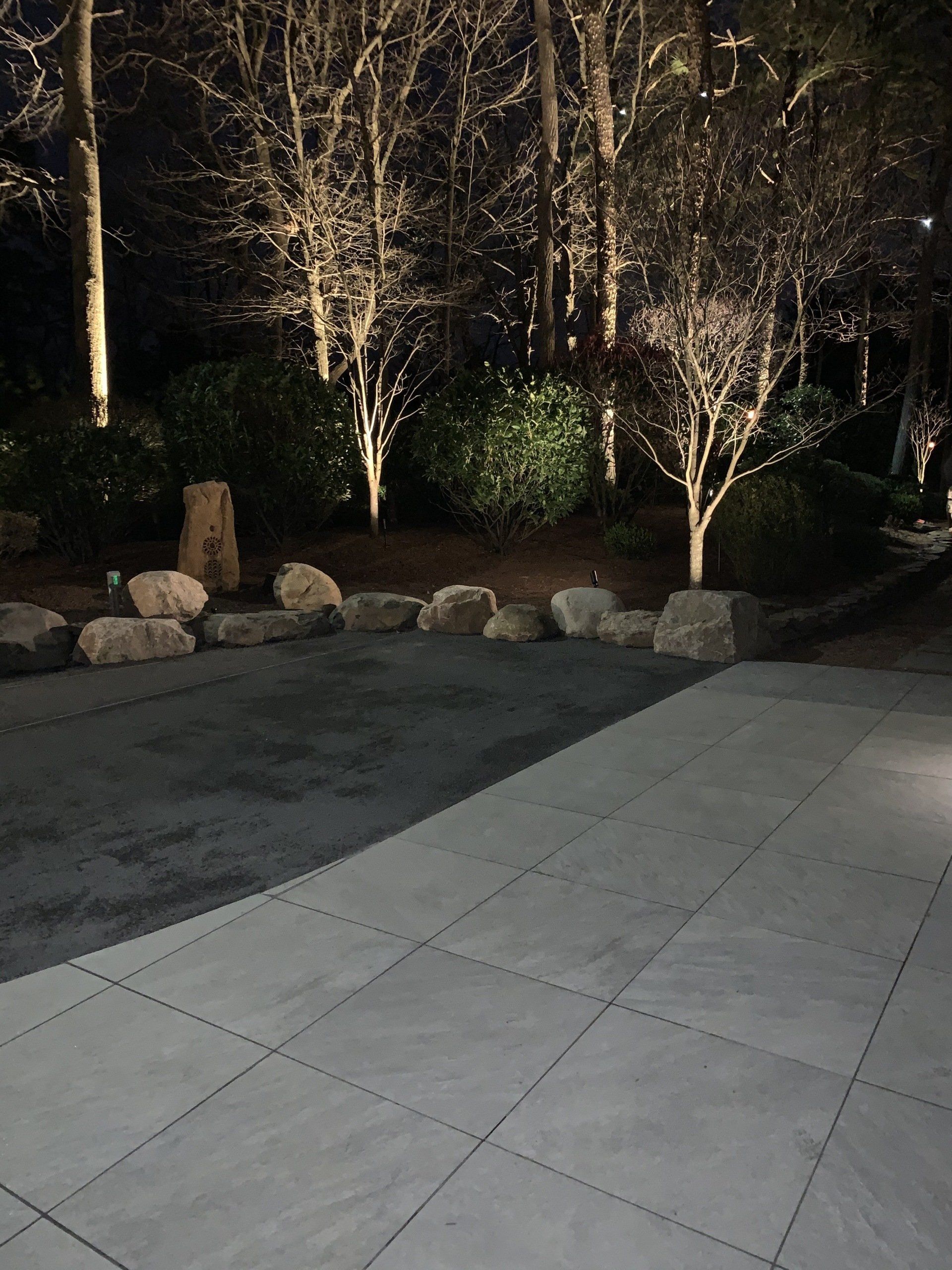A patio is lit up at night with trees in the background