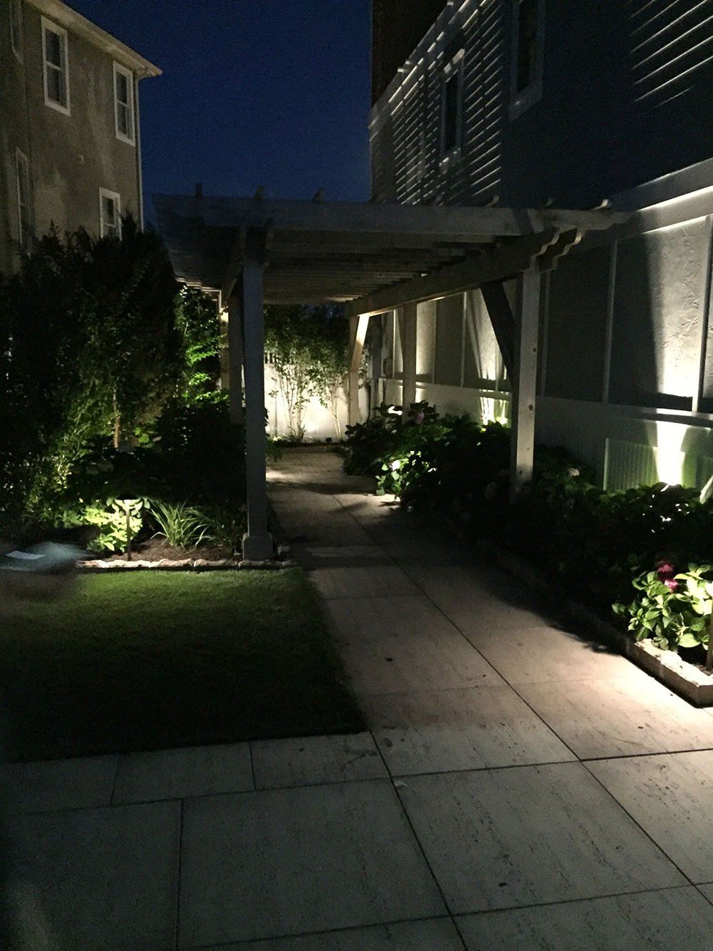 A walkway between two houses is lit up at night