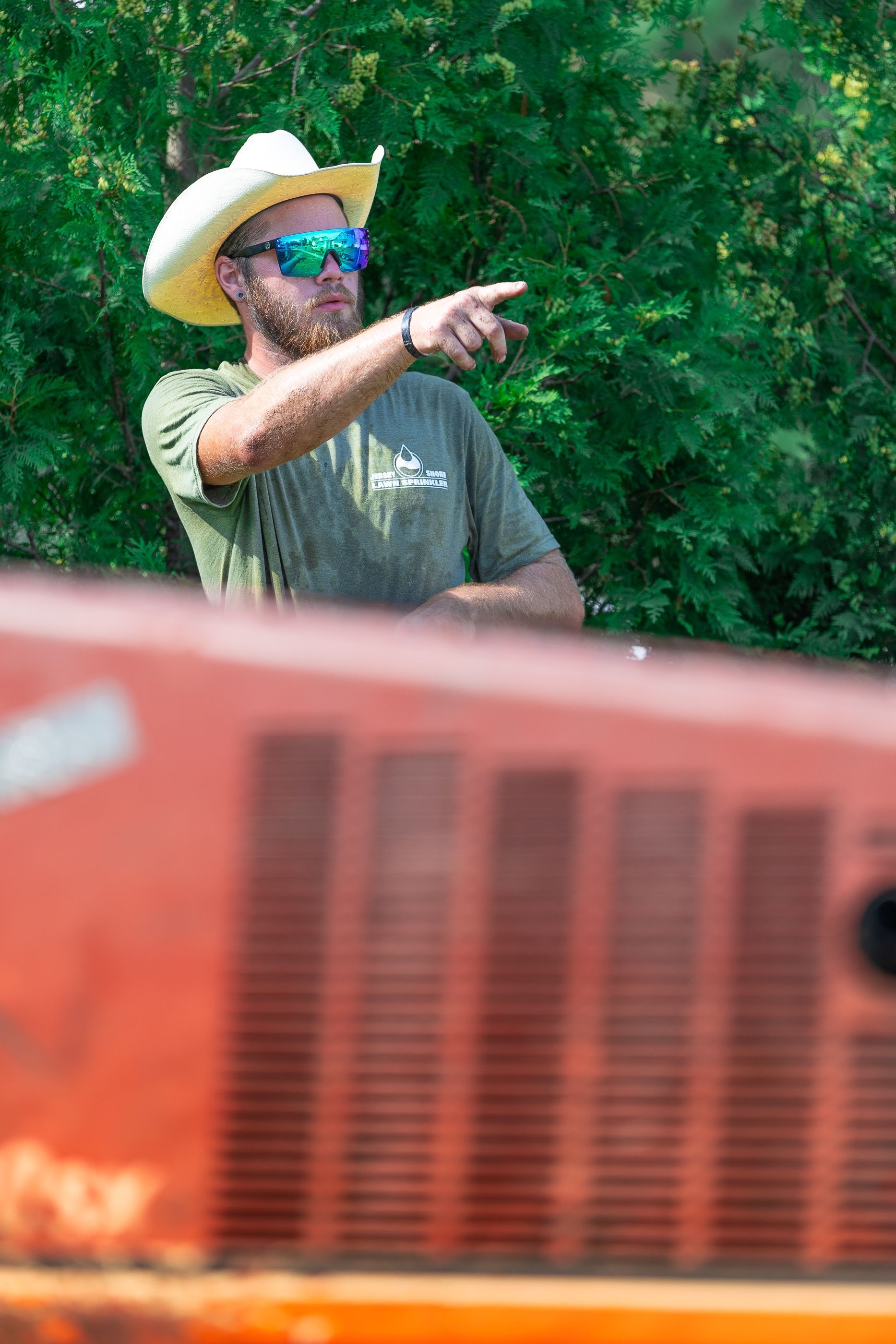 A man wearing a cowboy hat and sunglasses is pointing at something