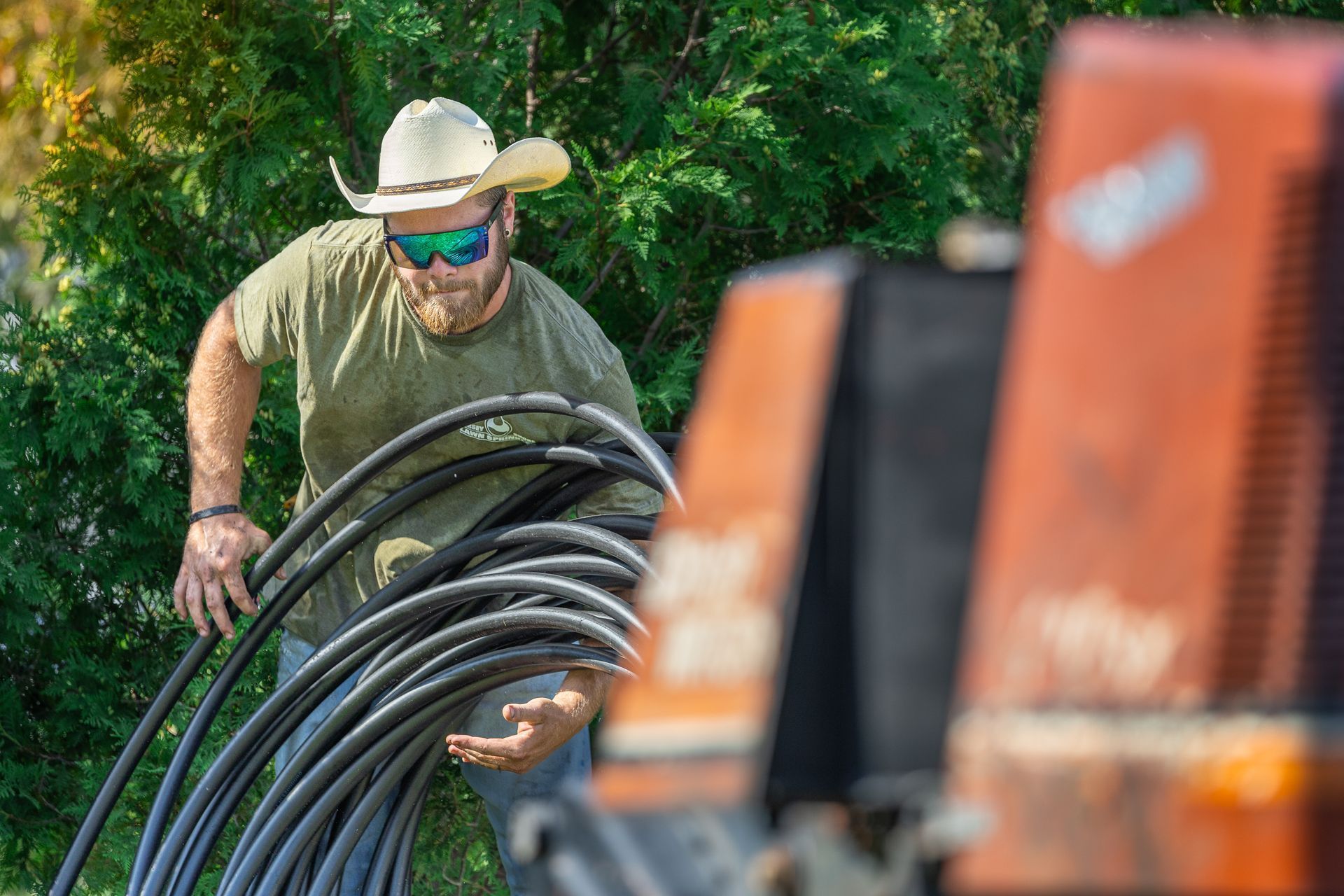 A man carrying a rolled up irrigation tubing