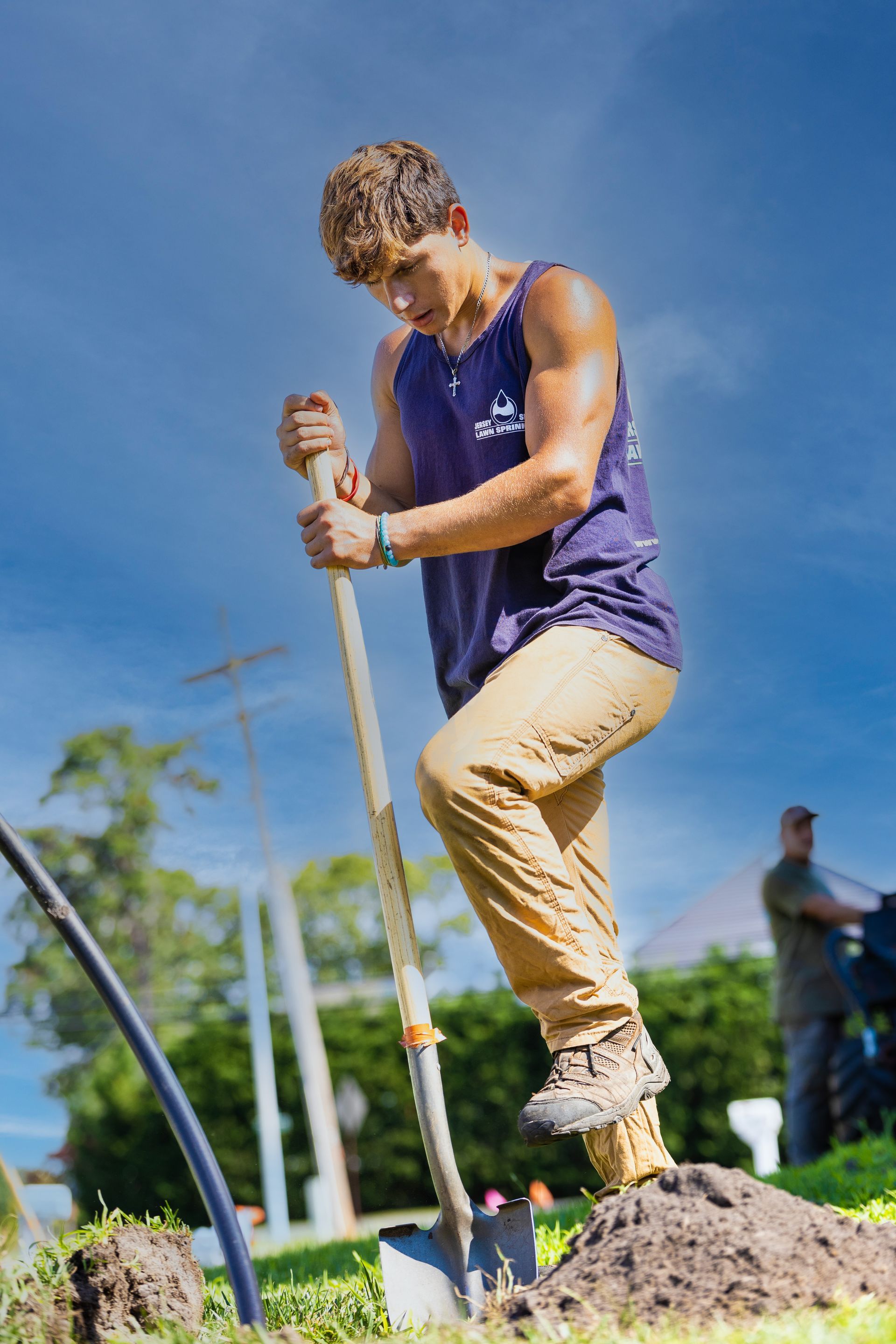 A young man is digging in the dirt with a shovel