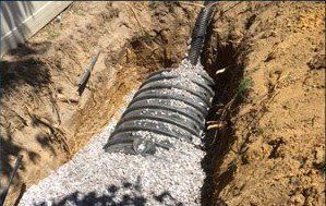 A drain pipe is being installed in a hole in the ground
