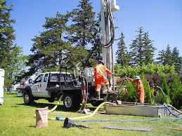 A truck is parked in a grassy field next to a drilling rig