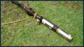 A water pump is sitting on top of a lush green field