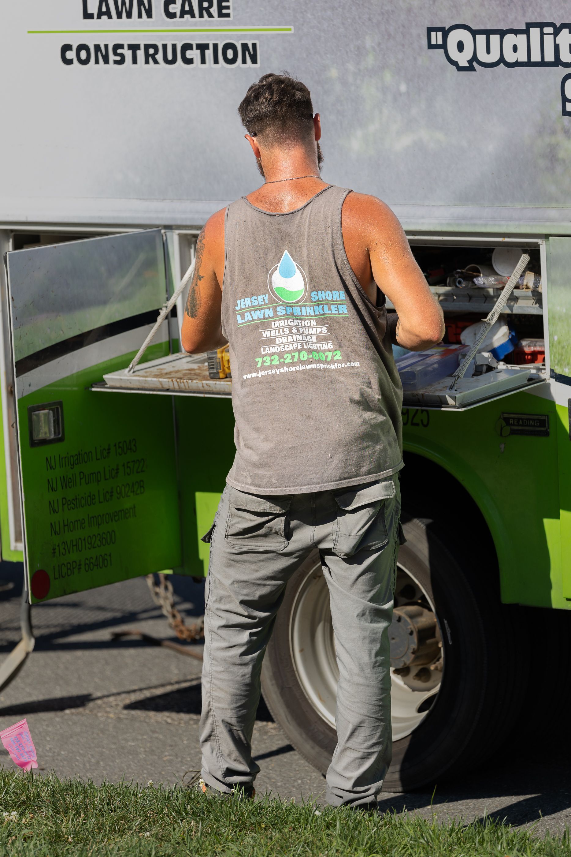 A man is standing in front of a lawn care truck