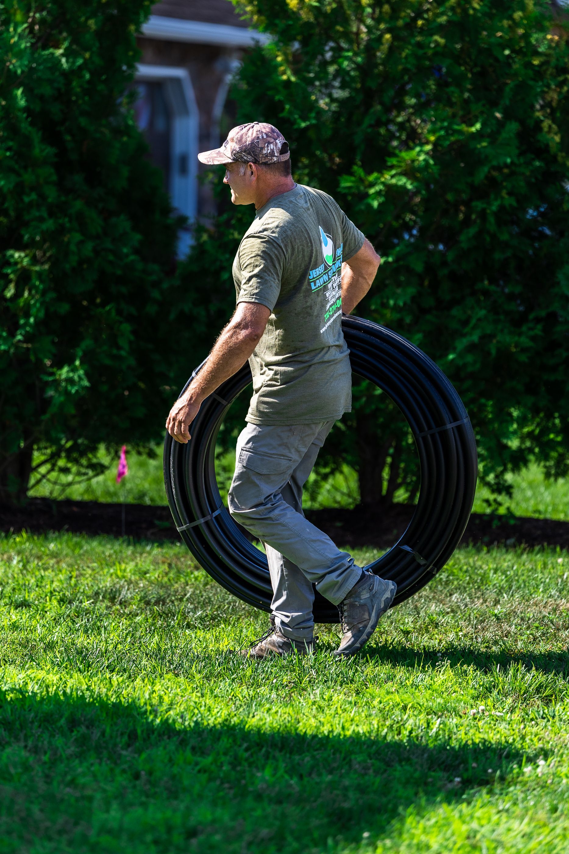 A man carrying a hose in a yard
