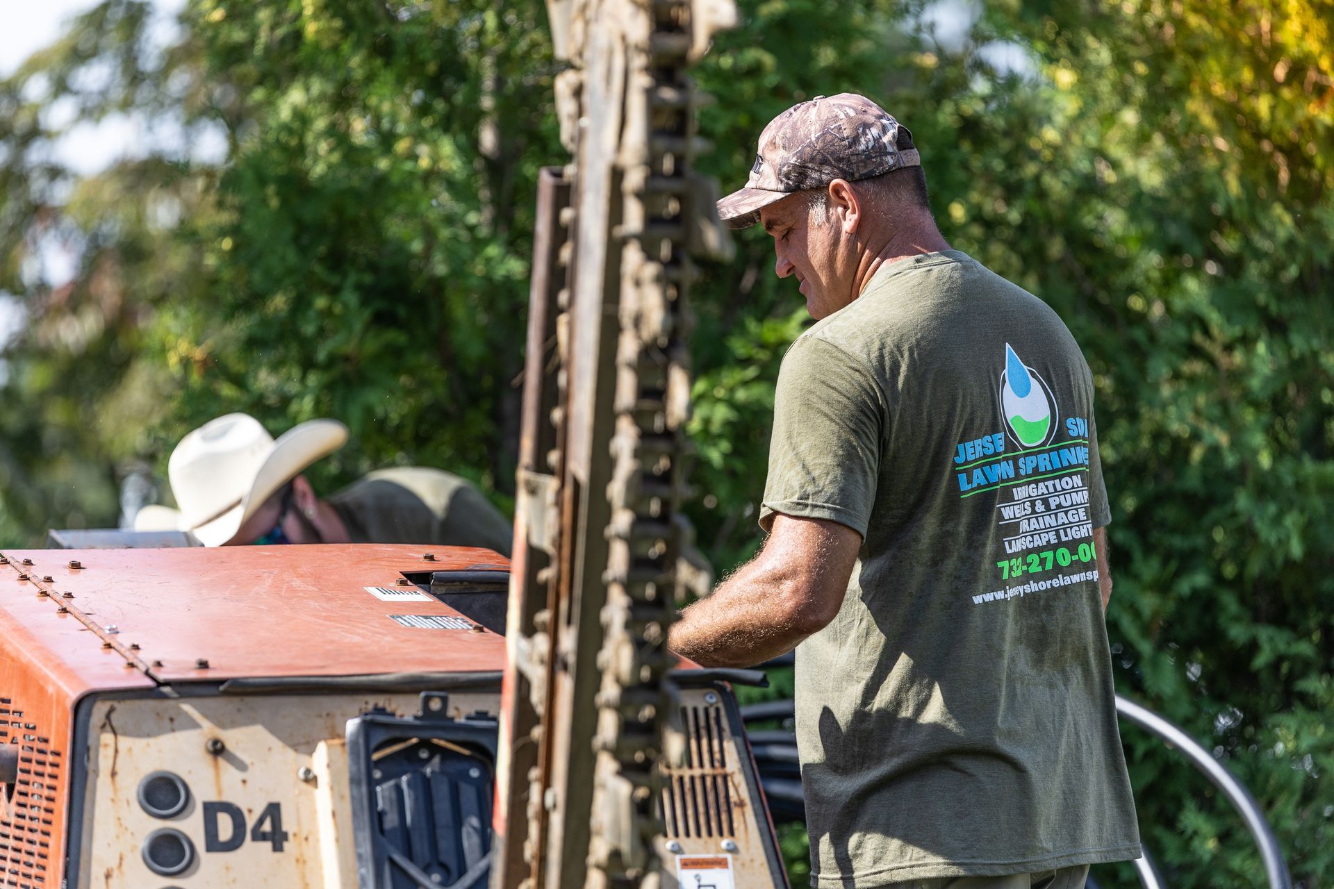A man in a green shirt is working on an excavator