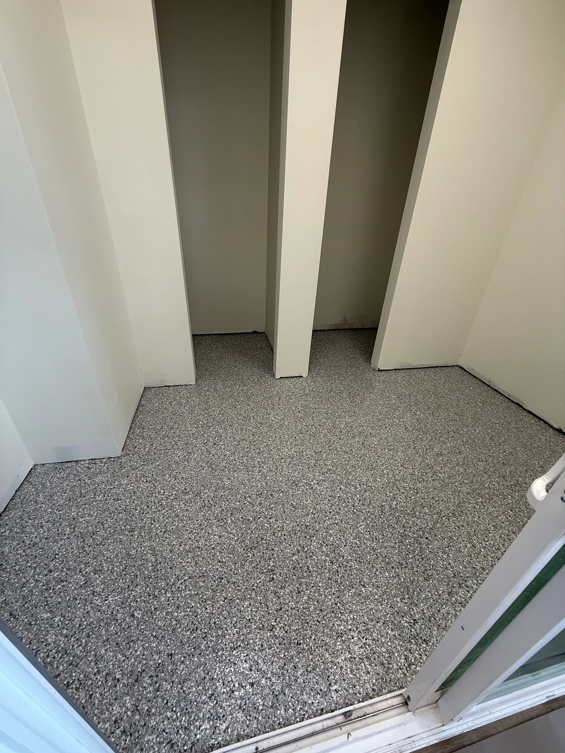 Open closet with speckled carpet and white walls, viewed from the doorway.