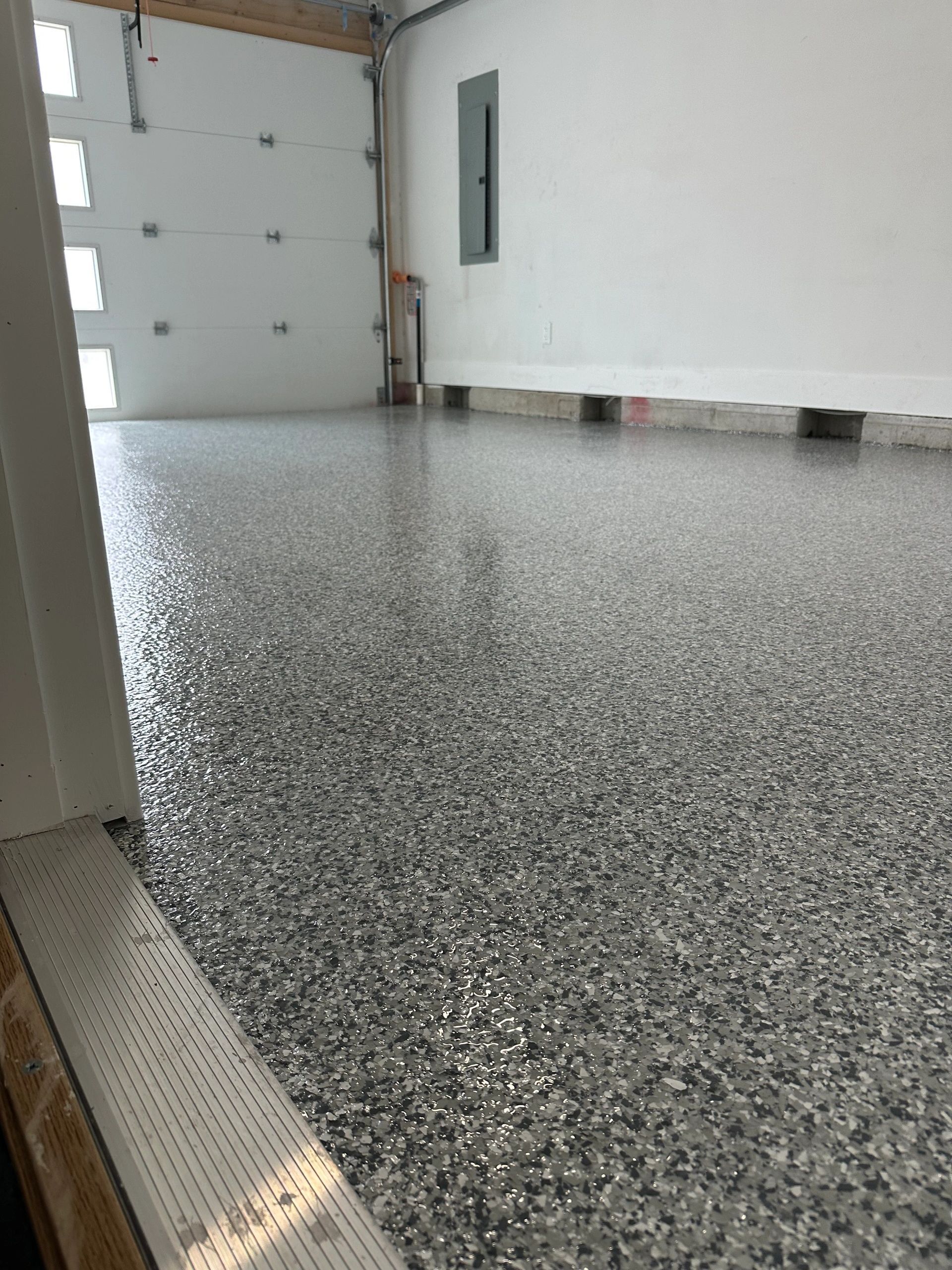 Empty garage with speckled epoxy floor and white walls
