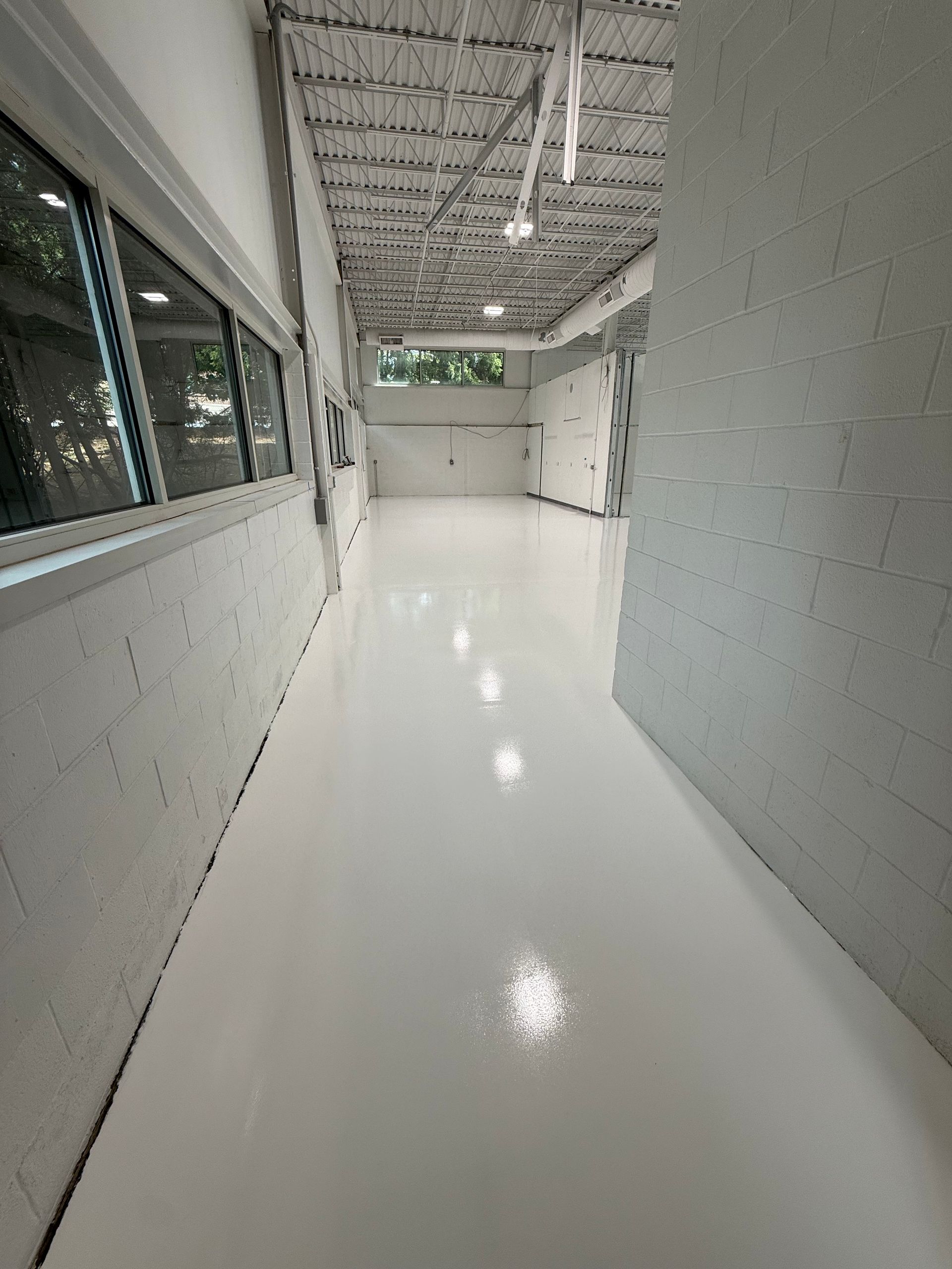 Bright white hallway with glossy floor, gray walls, and windows on the left.