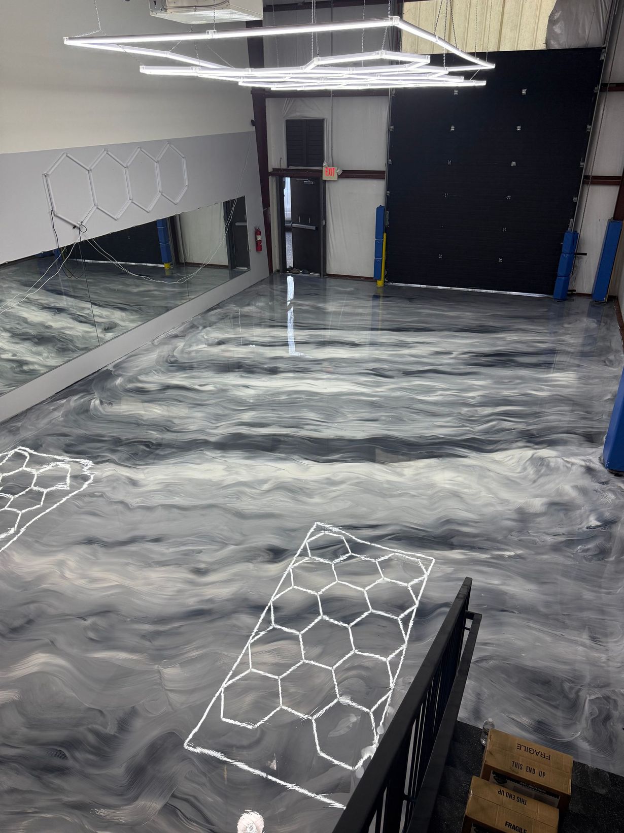 Empty room with glossy gray marbled floor, mirrors on left wall, and black wall panels.