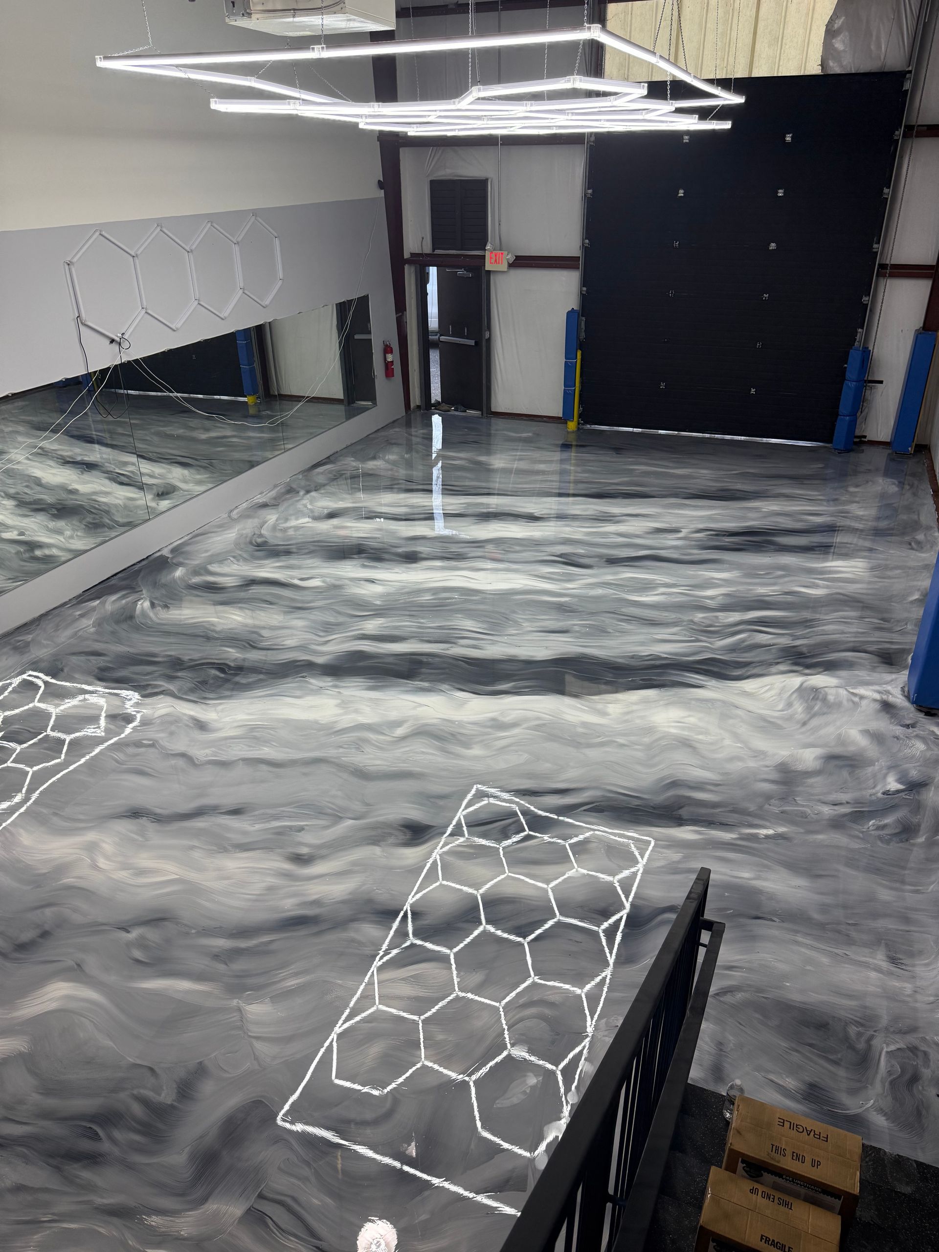 Marble-pattern epoxy floor in a room under construction, with white wall panels and overhead lights