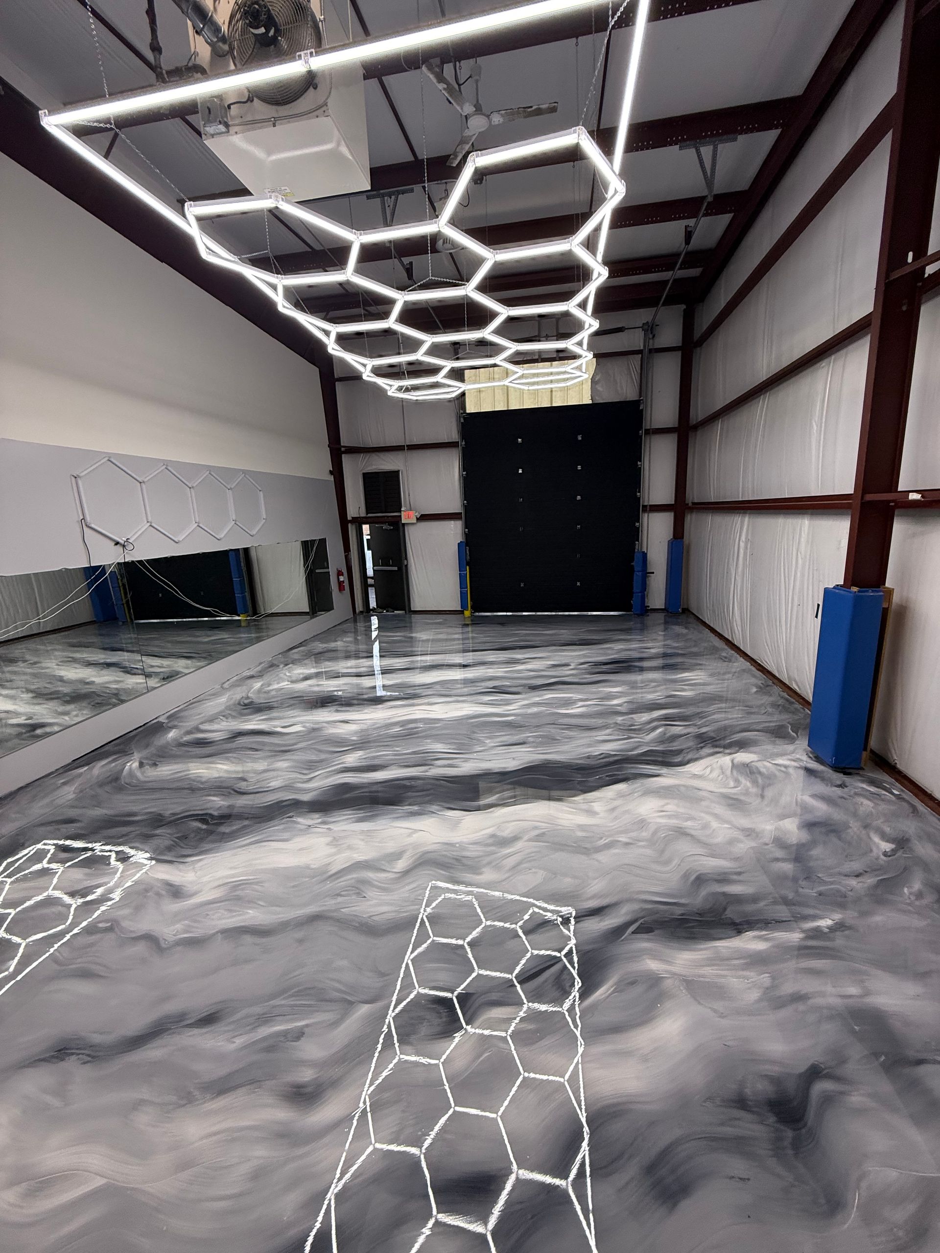 Empty industrial room with glossy gray floor and geometric hexagon lights on the ceiling