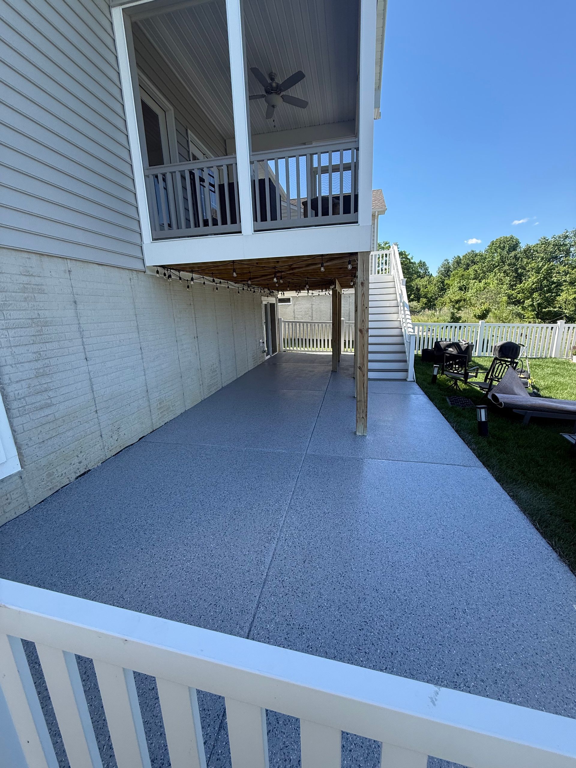 Raised house deck and gravel walkway beside a white home on a sunny day