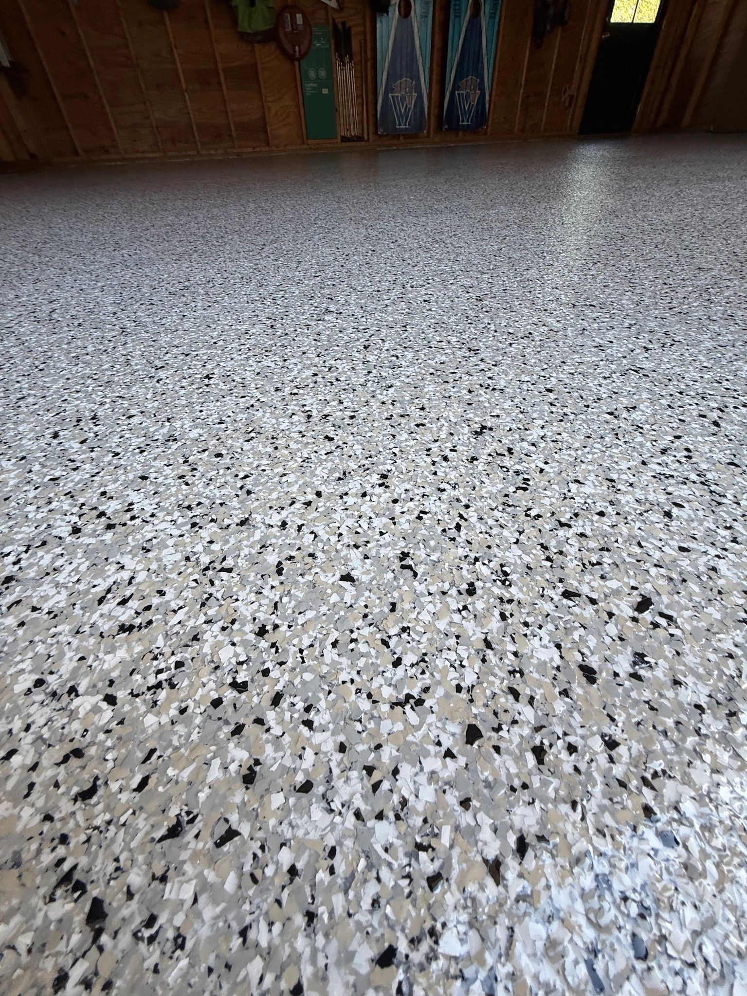 Speckled terrazzo floor with a wooden wall and small plant at the far end