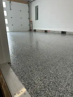 Empty garage with gray speckled epoxy floor and white walls
