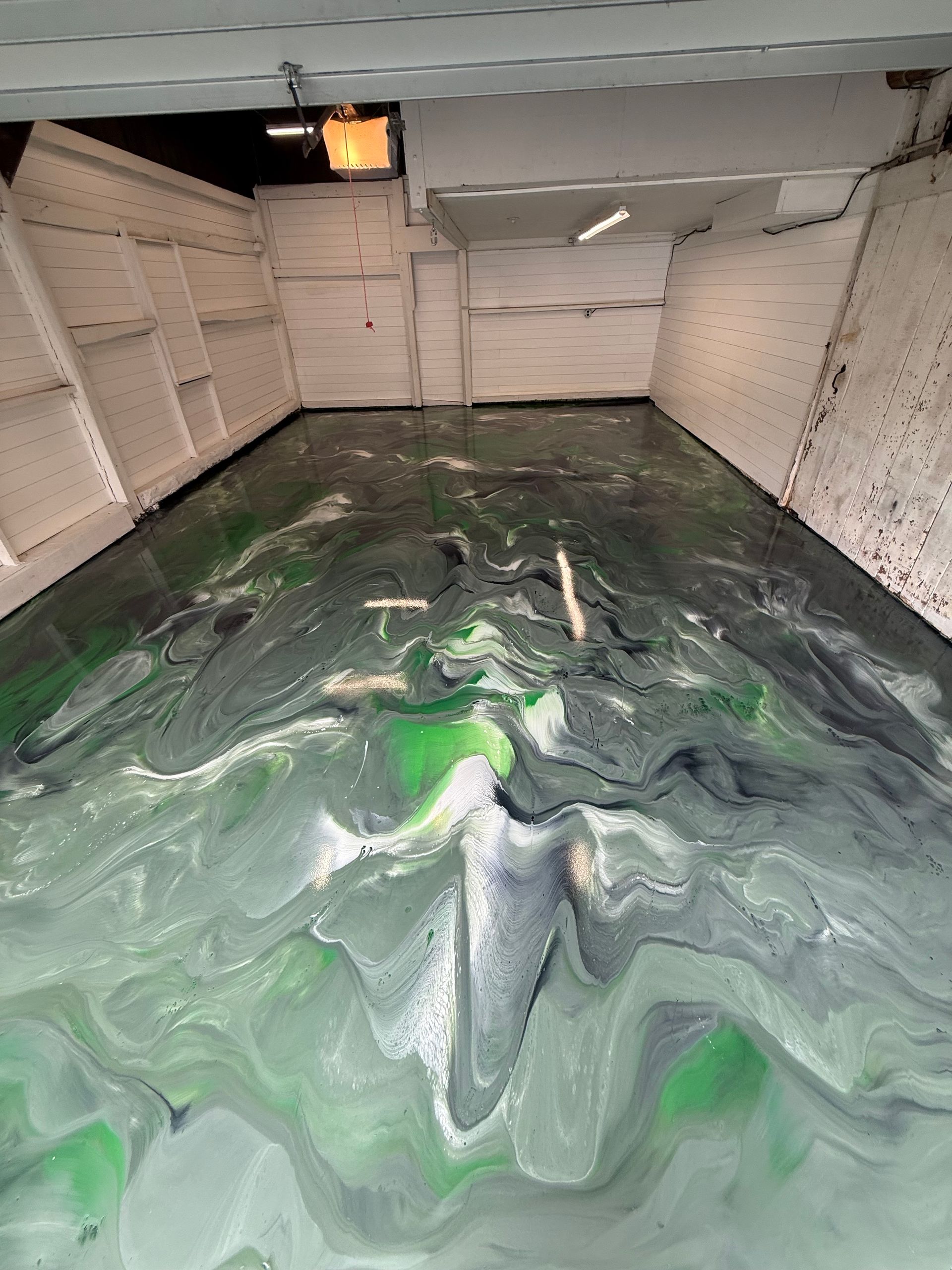Interior of a cargo hold with green liquid sloshing across the floor and white walls.