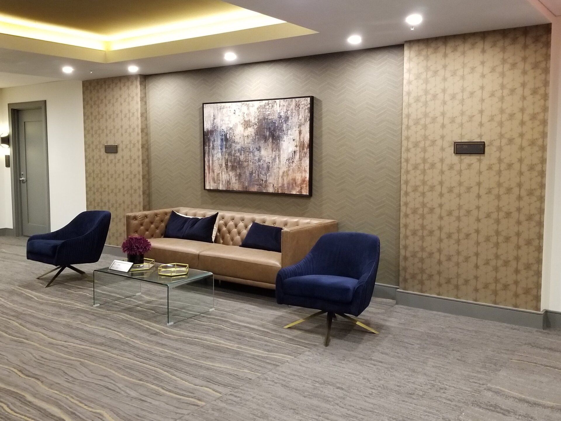 A living room with a couch, chairs, a coffee table and a painting on the wall