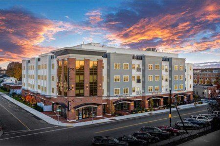 An aerial view of a large apartment building with cars parked in front of it at sunset