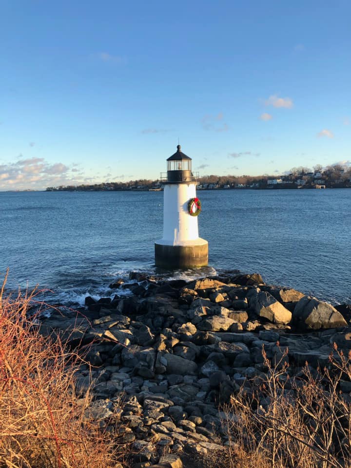 A lighthouse is sitting on a rocky shoreline next to the ocean